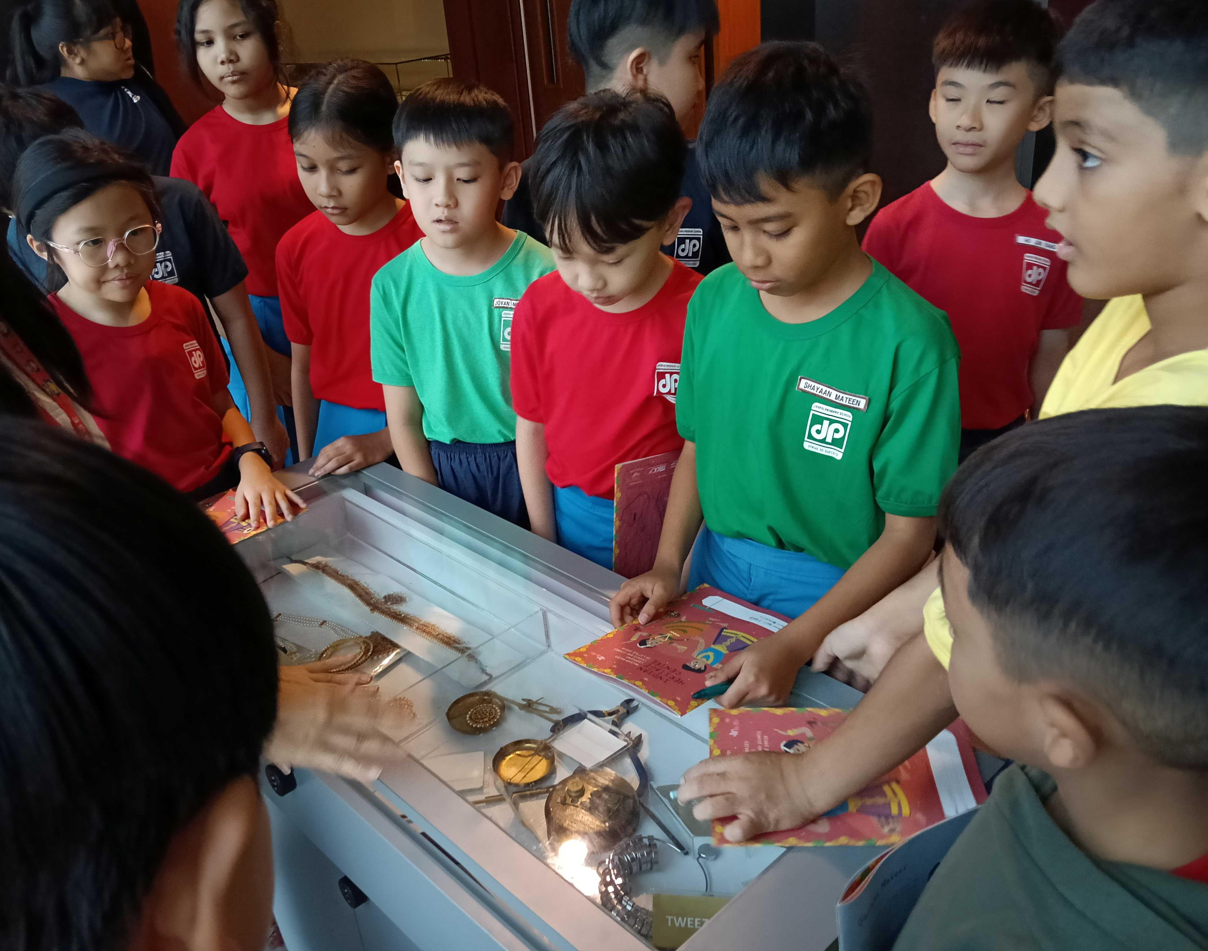 Primary 5 students gathering around the artefacts to learn more about traditional Indian jewellery at the Indian Heritage Centre.